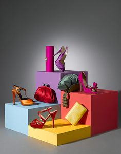 several different types of shoes and purses on colorful blocks with one woman's foot in the middle