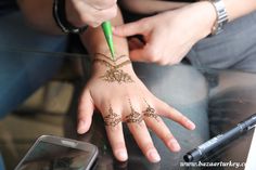 two people with henna tattoos on their hands and one holding a green pen while the other holds a cell phone