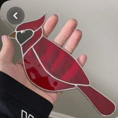 a hand holding a stained glass bird ornament in the shape of a cardinal