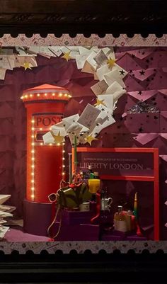 a window display with lots of items on the windowsills and in front of it is a red phone booth