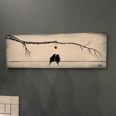 two birds sitting on a branch with a red heart hanging from it's side