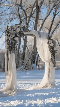 an outdoor wedding ceremony set up in the snow with white draping and flowers