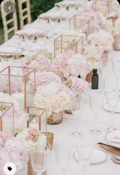 a long table with pink and white flowers in vases, candles and napkins