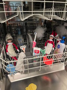 two elf dolls are sitting in the dishwasher