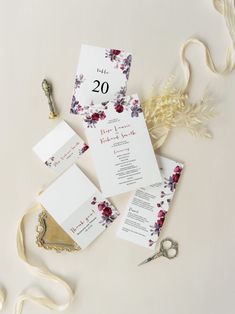 the wedding stationery is laid out on top of each other with scissors and flowers