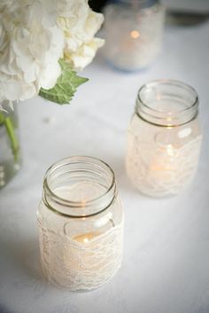 two mason jars filled with white flowers on a table