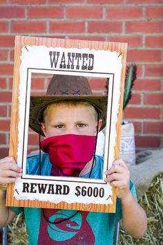 a young boy wearing a red face mask and holding up a wanted reward sign in front of him