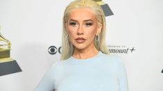 lady with blonde hair and blue dress posing in front of an award for best performance