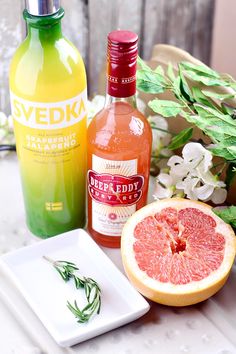 grapefruit, orange juice, and gin are on a table next to flowers