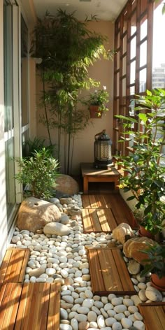 an outdoor area with rocks and plants on the floor, along with wooden benches and tables