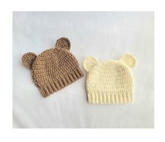 two crocheted hats sitting next to each other on top of a white surface