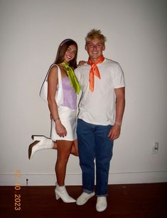 a man standing next to a woman in a white shirt and orange neck tie on