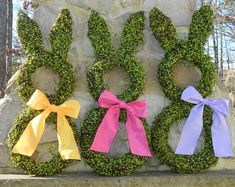 three wreaths with bows are sitting on a stone wall in front of a tree