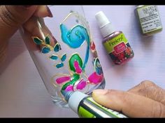 someone is painting on a glass bottle with acrylic paint and some other supplies