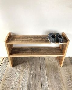 a pair of shoes sitting on top of a wooden shelf next to a white wall