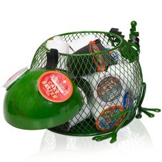 a green basket filled with assorted items on top of a white table next to a bottle