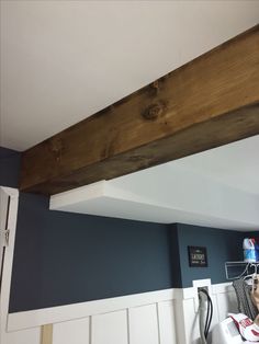 a kitchen with blue walls and wood beams above the stove top, along with white cupboards