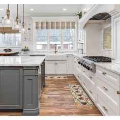 a large kitchen with white cabinets and wood flooring, along with marble counter tops