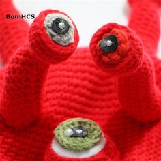 two red crocheted stuffed animals with eyes and nose are shown in front of the camera