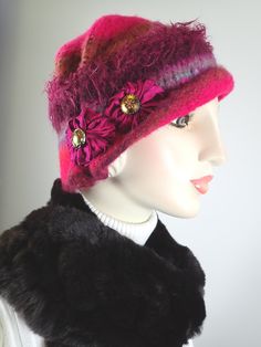 Add some warmth and whimsy to your fall and winter wardrobe with this fun hand knitted boiled and felted 100 percent wool warm winter cloche. This cute wool hat will keep you warm! Dress it up with an oversize shawl or throw it on with a jean jacket. Colors include fuchsia pink, rust and blue with other colorful fun fibers that pop out of the felt for added texture. Embellished with two handmade silk rosettes topped with iridescent vintage glass buttons. Rolled asymmetrical brim for additional i Hand Knitted Wool Hats, Pink Winter Mini Hat One Size Fits Most, Fitted Pink Mini Hat For Winter, Knitted Pink Hat For Fall, Pink Fitted Mini Hat For Winter, Handmade Winter Cloche Hat, Pink Felt Hat With Curved Brim For Winter, Pink Short Brim Felt Hat For Winter, Pink Curved Brim Felt Hat For Winter