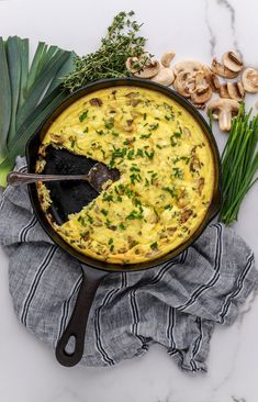 an omelet with mushrooms and green onions in a skillet