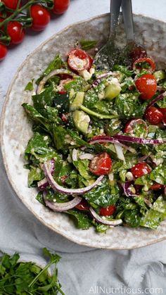 a salad with tomatoes, onions and cucumbers in a bowl on a table