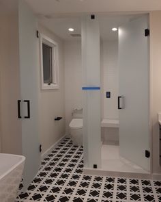 an empty bathroom with black and white floor tiles on the walls, toilet and shower stall