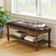 a wooden bench sitting in front of a window next to a potted plant and books