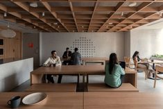 people are sitting at tables in an open space with wooden beams on the ceiling and walls