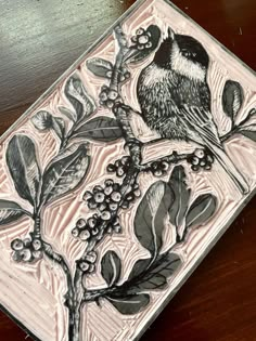 a bird sitting on top of a wooden table next to some leaves and berries in front of it