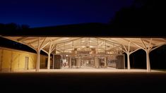 an empty building lit up at night with lights on the roof and doors open in front of it