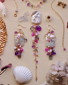 several different types of jewelry are laying out on the table next to shells and seashells