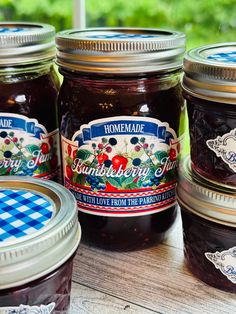 four jars of jam sitting on top of a wooden table