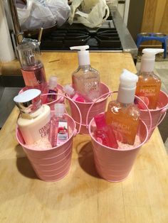 pink buckets filled with soap and lotion on top of a wooden table