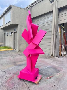 a pink sculpture sitting in front of a garage