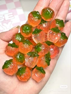 small gummy bears are in the palm of someone's hand with green and orange gummy bears on it