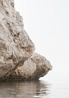 a man standing on top of a rock next to the ocean