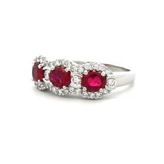 Early 21st Century Estate 18kt white gold ring featuring a center row of 3 prong set oval mixed cut ruby with a semi-bezel set round brilliant cut diamond set in-between each.  The center is framed with shared prong set round brilliant cut diamonds. The ring is finished with a bright polish.  Gemstones: 3 oval mixed cut ruby, 0.90 carats total weight (calculated in mounting) transparent vivid red color Gemstones: 34 round brilliant cut diamonds, 0.42 carats total weight (calculated in mounting) Formal Ruby Three Stone Ring With Diamonds, Oval Ruby Ring With Three Diamonds, Oval Three Stone Ruby Ring With Diamonds, Red Three-stone Ruby Ring, Red Ruby Three Stone Round Cut Ring, Red Three Stone Round Cut Ruby Ring, Red Three Stone Ruby Ring, Formal White Gold Ruby Ring With Three Stones, Oval Red Ruby Ring With Three Stones