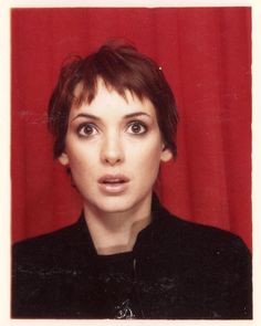 a woman with short hair and black shirt looking at the camera while wearing an eye ring