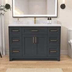 a white toilet sitting next to a gray vanity with a mirror on top of it