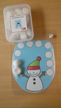 a blue toilet with a snowman sticker on the lid and marshmallows next to it