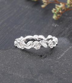 an image of a wedding ring on top of a stone slab with flowers in the middle