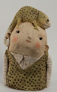 a ceramic sculpture of a man with a lizard on his head