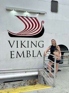 a woman standing on the steps of a boat next to a sign that says viking emblaa