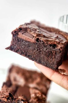 a hand holding a piece of chocolate brownie