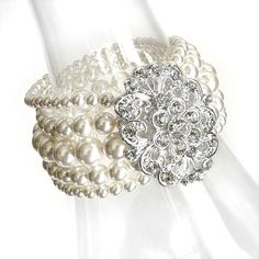 two white bracelets with pearls and crystal stones on them, one in the shape of a flower