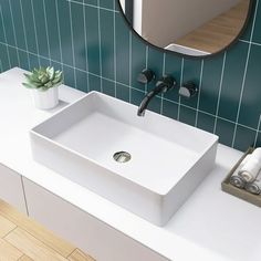 a white sink sitting on top of a bathroom counter next to a green tiled wall