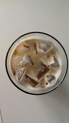 an iced drink in a glass with ice cubes on the rim, sitting on a white surface