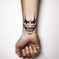 a person's hand with a tattoo on it that has a joker face and teeth