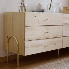 a wooden dresser sitting on top of a hard wood floor next to a white wall